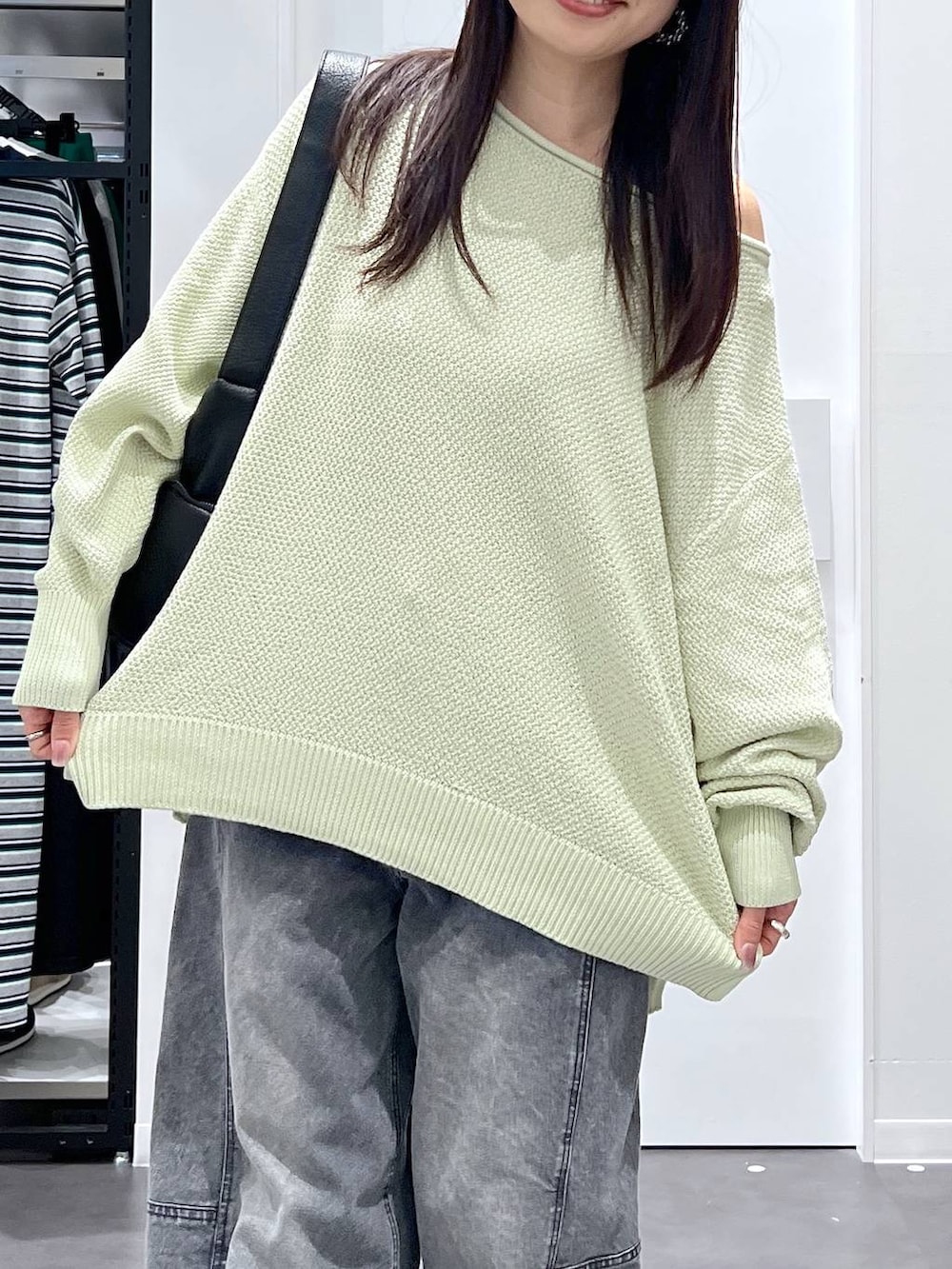 ブラック系のショルダーバッグ、ブラック系のスニーカー、グリーン系のニット/セーターを着用したレディースの春コーディネートの4枚目の写真