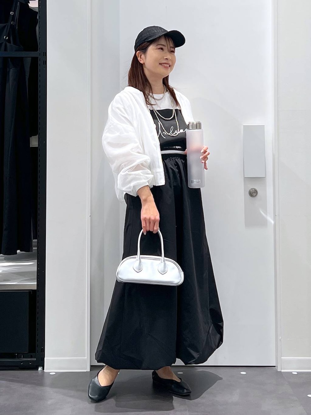 シルバー系のボストンバッグ、ブラック系のパンプス、ブラック系のスカートを着用したレディースの春コーディネートの3枚目の写真