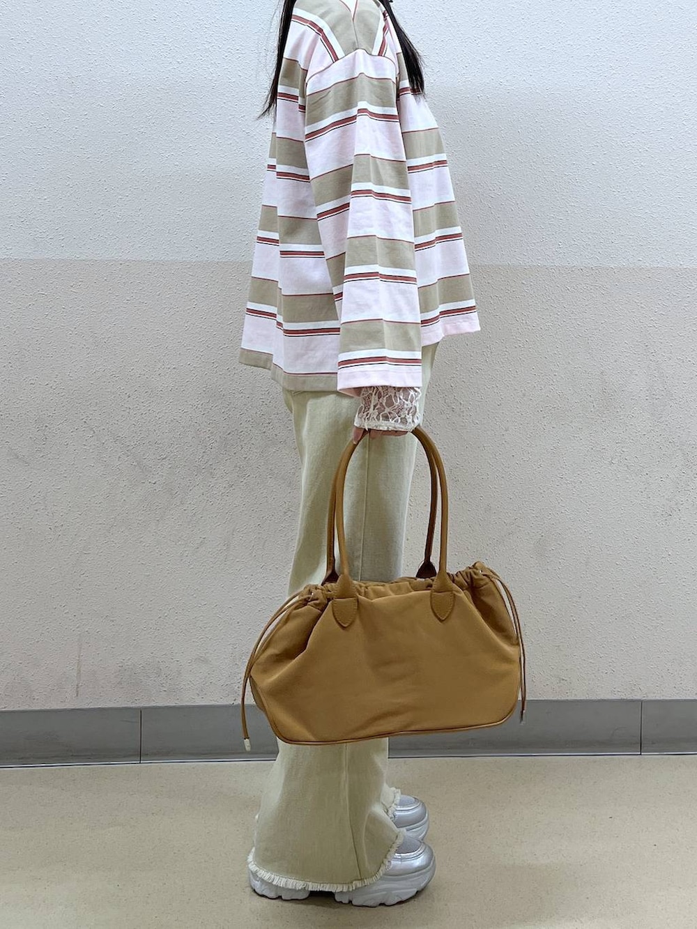 ホワイト系のTシャツ/カットソー、ブラウン系のハンドバッグ、ベージュ系のデニムパンツを着用したレディースの冬コーディネートの2枚目の写真