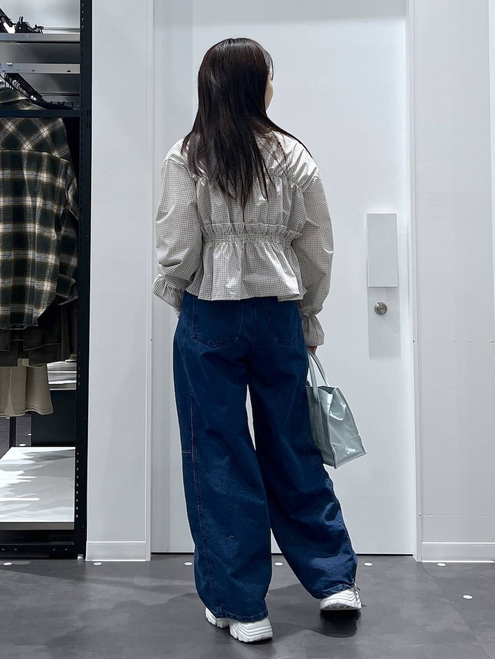 グリーン系のトートバッグ、ブルー系のデニムパンツ、ベージュ系のシャツ/ブラウスを着用したレディースの春コーディネートの3枚目の写真