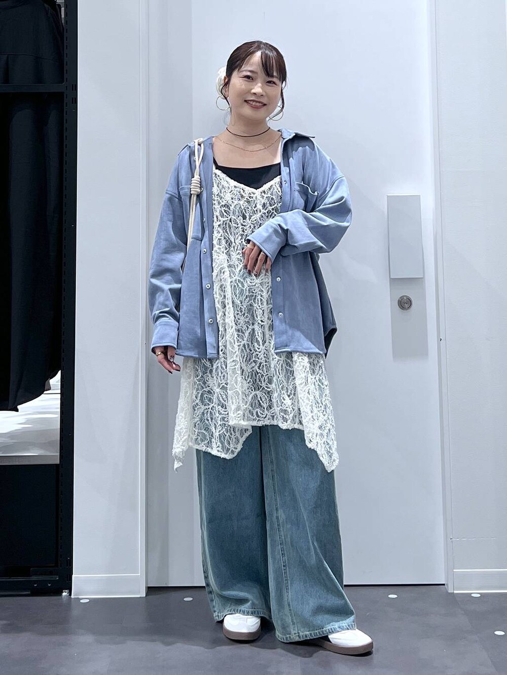 ホワイト系のスニーカー、ホワイト系のショルダーバッグ、ブルー系のデニムパンツを着用したレディースの秋コーディネートの5枚目の写真