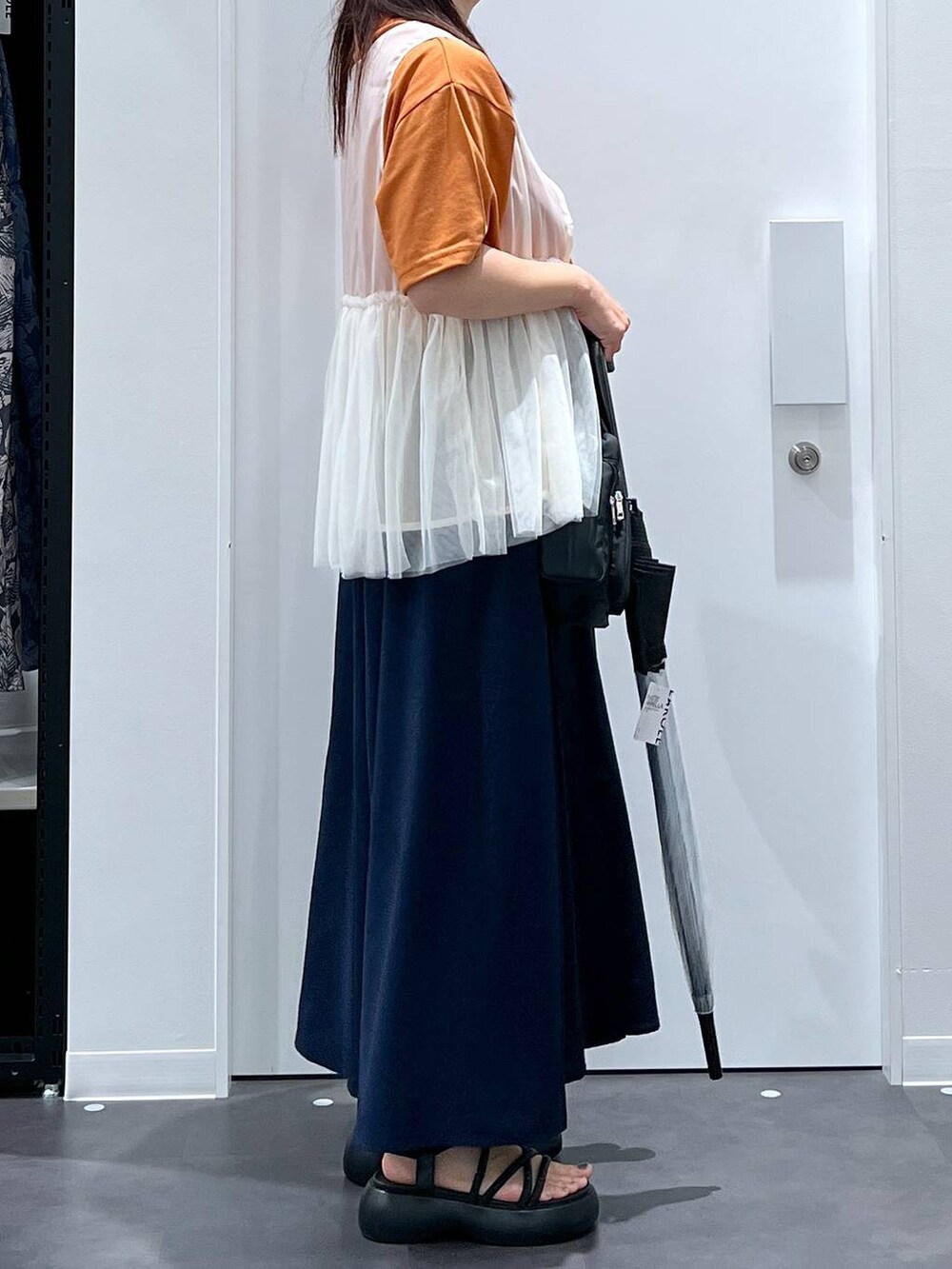 ブラック系のサンダル、オレンジ系のTシャツ/カットソー、ベージュ系のベストを着用したレディースの夏コーディネートの2枚目の写真