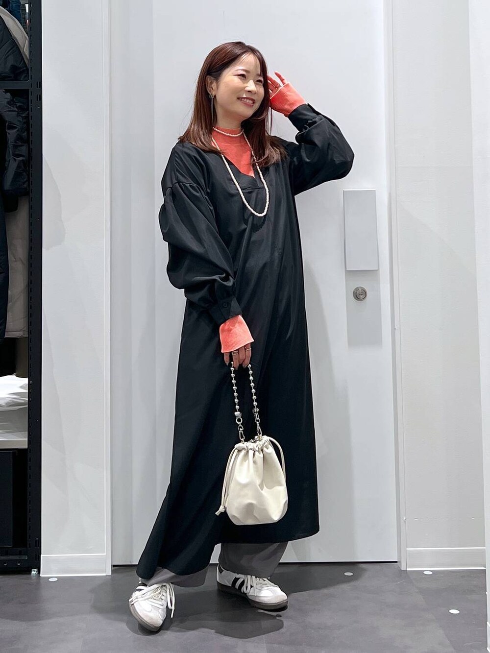 ベージュ系のショルダーバッグ、オレンジ系のニット/セーター、グレー系のその他パンツを着用したレディースの春コーディネートの3枚目の写真