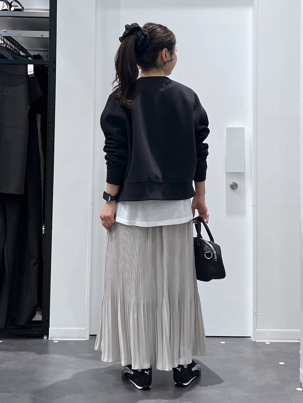 ブラック系のスニーカー、ブラック系のカーディガン/ボレロ、ベージュ系のスカートを着用したレディースの春コーディネートの3枚目の写真