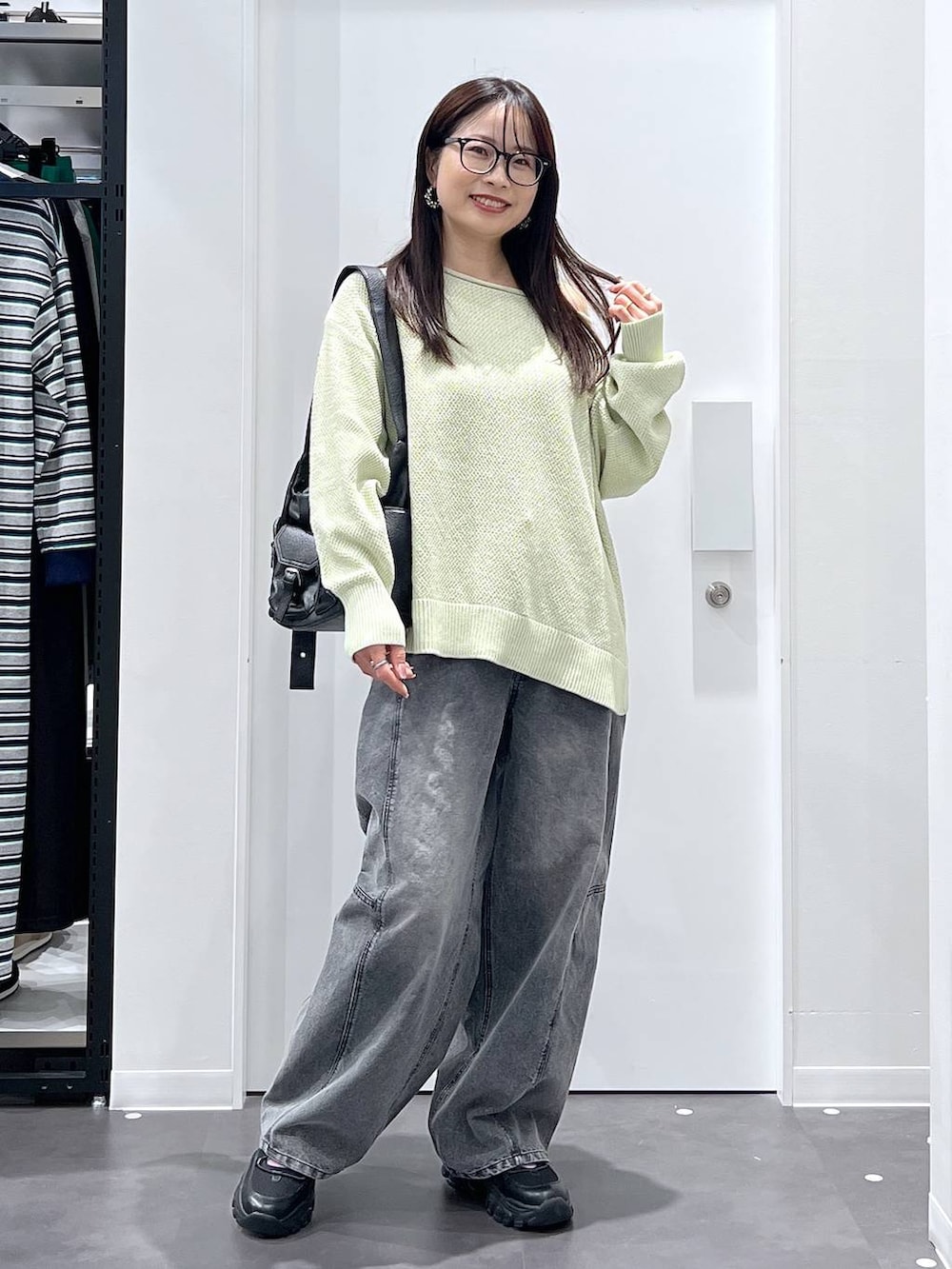 ブラック系のショルダーバッグ、ブラック系のスニーカー、グリーン系のニット/セーターを着用したレディースの春コーディネートの5枚目の写真