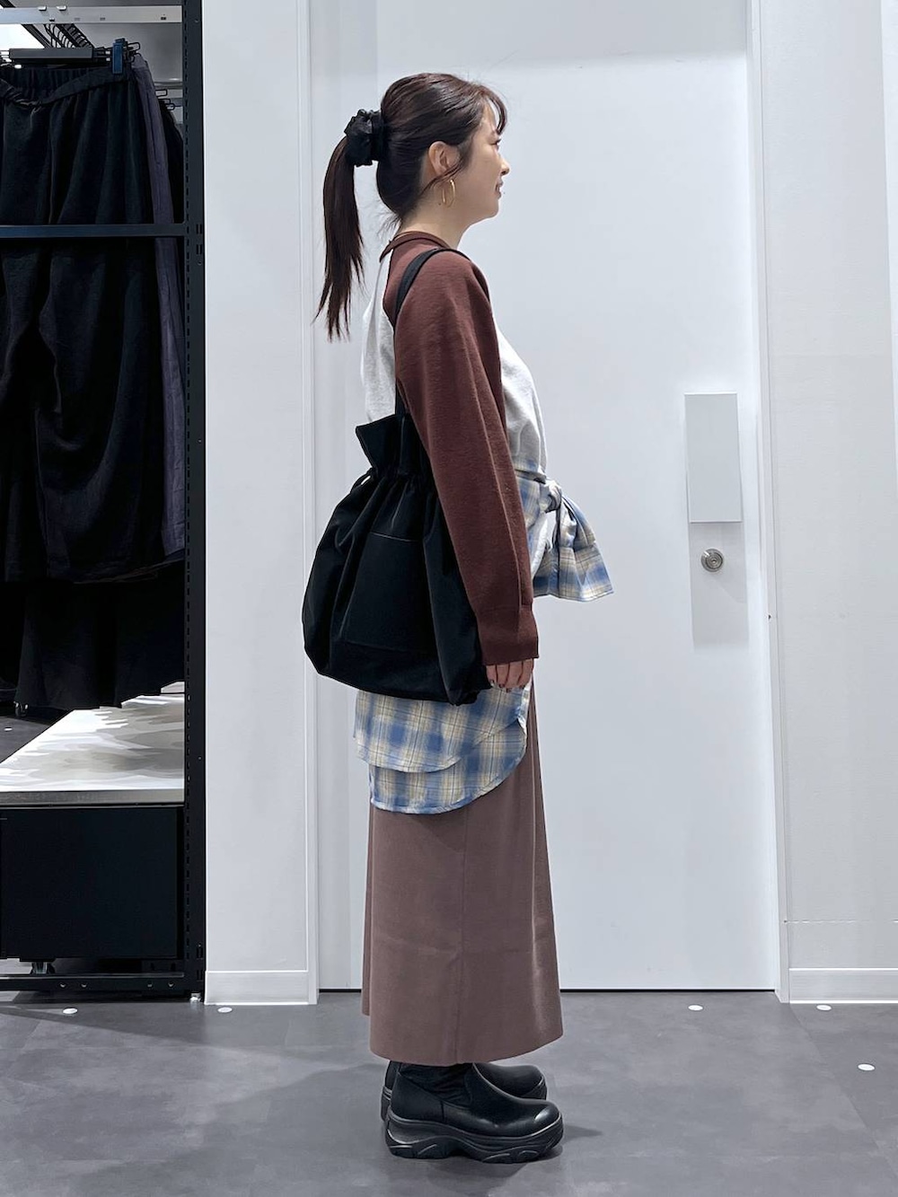 ブラック系のトートバッグ、ブラック系のブーツ、ブラウン系のニット/セーターを着用したレディースの秋コーディネートの2枚目の写真