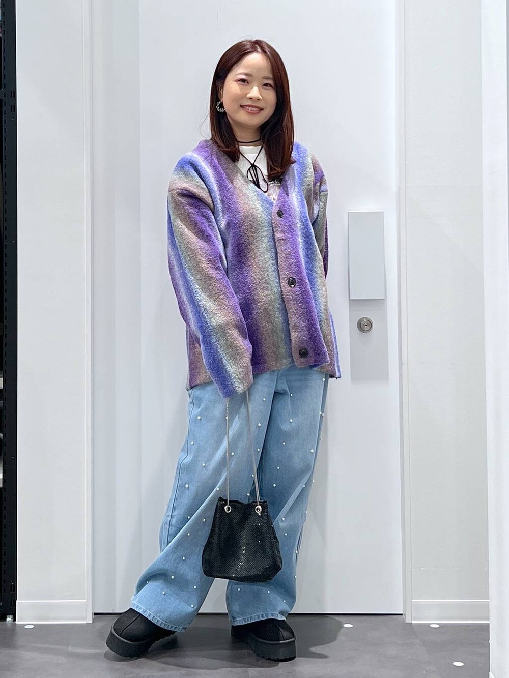 ブラック系のスリッポン、パープル系のカーディガン/ボレロ、ブルー系のデニムパンツを着用したレディースの冬コーディネートの3枚目の写真