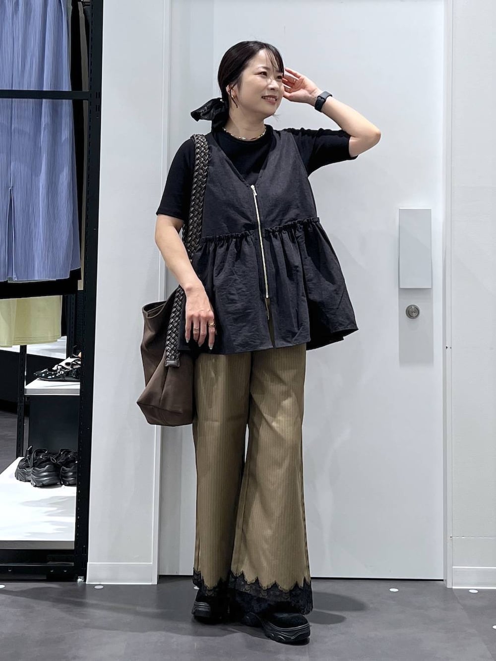 ブラウン系のショルダーバッグ、イエロー系のスラックス、ブラック系のベストを着用したレディースの夏コーディネートの5枚目の写真