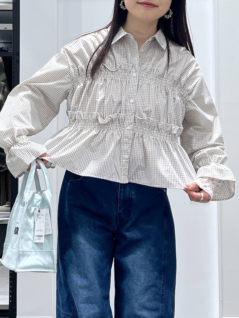 グリーン系のトートバッグ、ブルー系のデニムパンツ、ベージュ系のシャツ/ブラウスを着用したレディースの春コーディネートの4枚目の写真