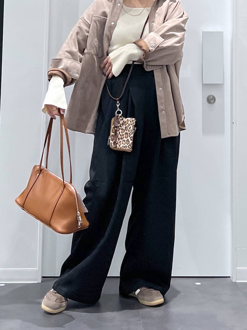 ブラウン系のボストンバッグ、ベージュ系のニット/セーター、ブラック系のその他パンツを着用したレディースの秋コーディネートの4枚目の写真