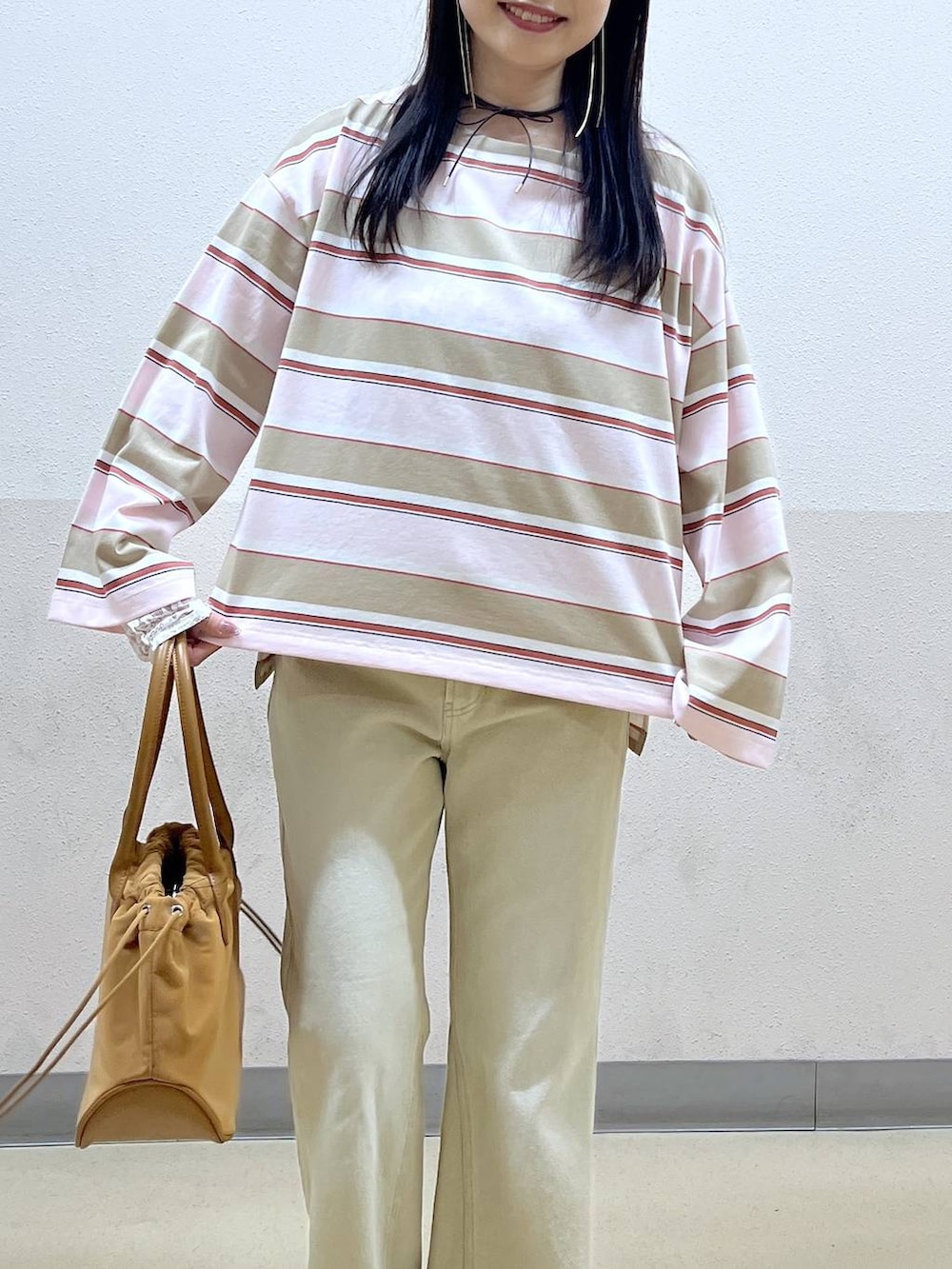 ホワイト系のTシャツ/カットソー、ブラウン系のハンドバッグ、ベージュ系のデニムパンツを着用したレディースの冬コーディネートの4枚目の写真