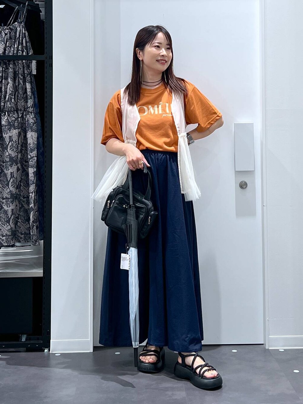 ブラック系のサンダル、オレンジ系のTシャツ/カットソー、ベージュ系のベストを着用したレディースの夏コーディネートの4枚目の写真