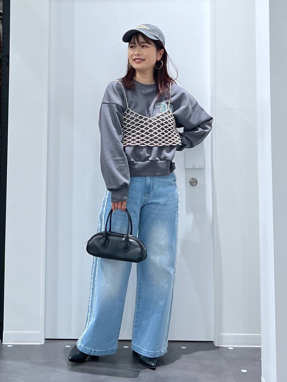 シルバー系のベスト、ブラック系のブーツ、ブラック系のボストンバッグを着用したレディースの冬コーディネートの3枚目の写真