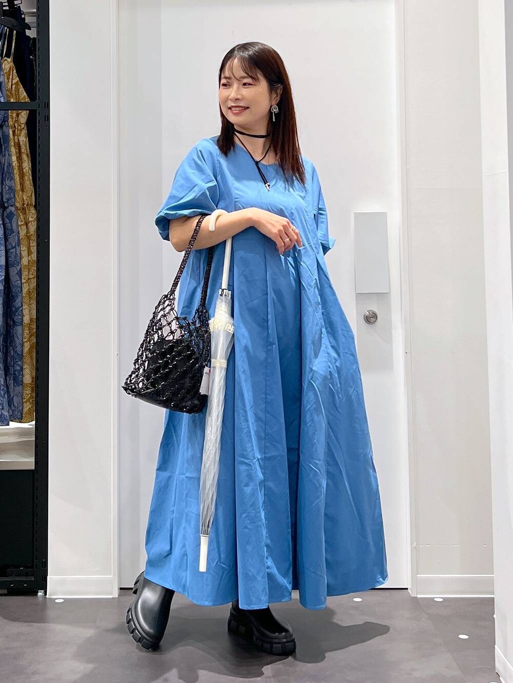 ブラック系のかごバッグ、ブラック系のレインシューズ、ブルー系のワンピースを着用したレディースの春コーディネートの6枚目の写真