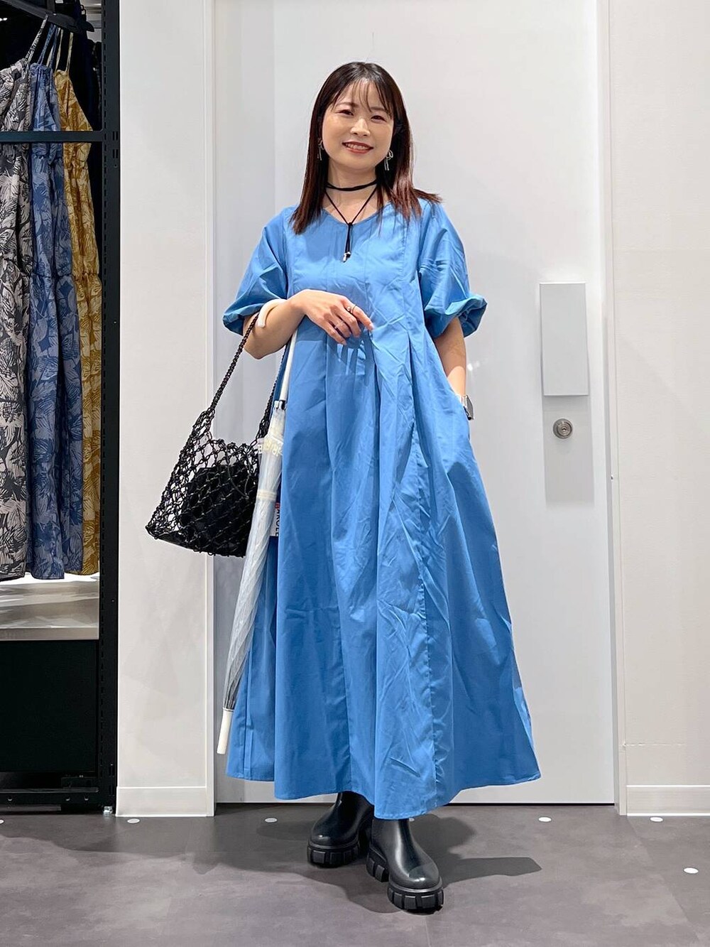 ブラック系のかごバッグ、ブラック系のレインシューズ、ブルー系のワンピースを着用したレディースの春コーディネートの5枚目の写真