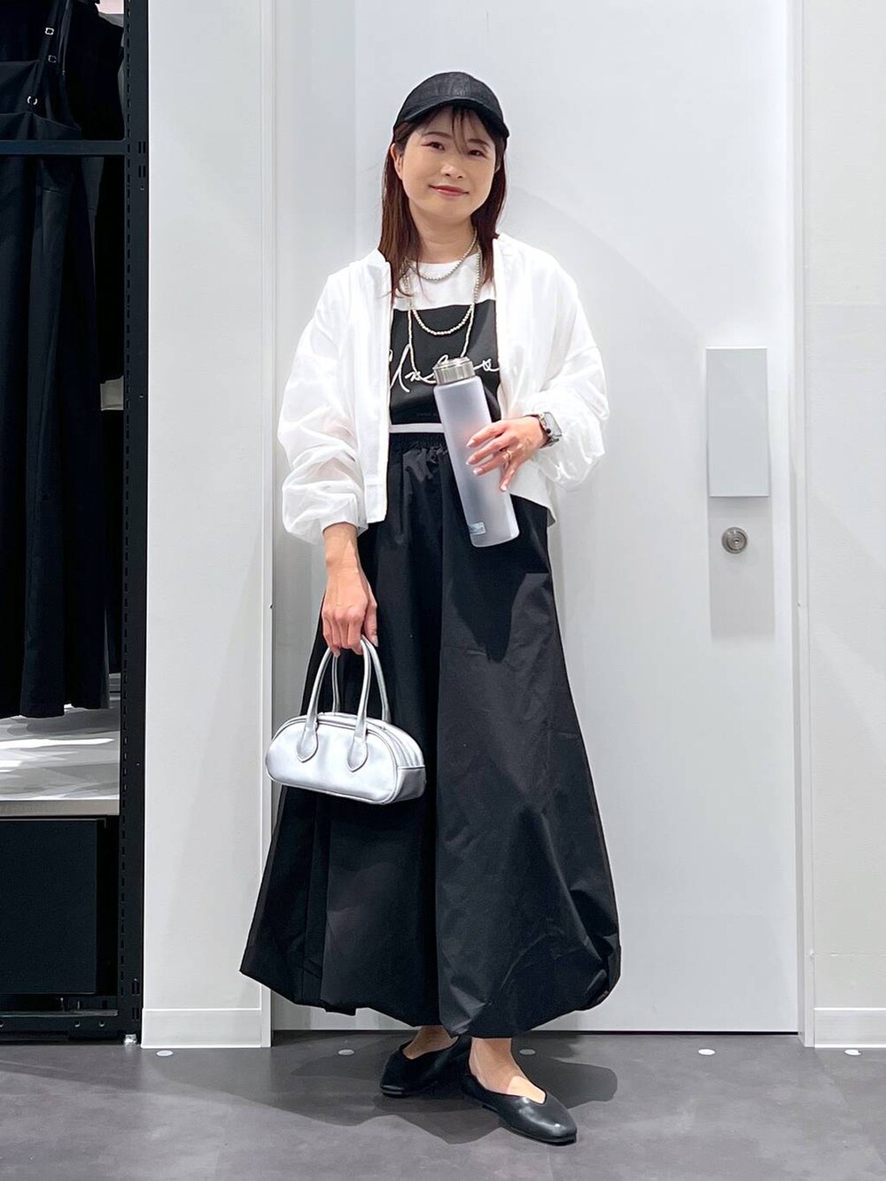 シルバー系のボストンバッグ、ブラック系のパンプス、ブラック系のスカートを着用したレディースの春コーディネートの4枚目の写真