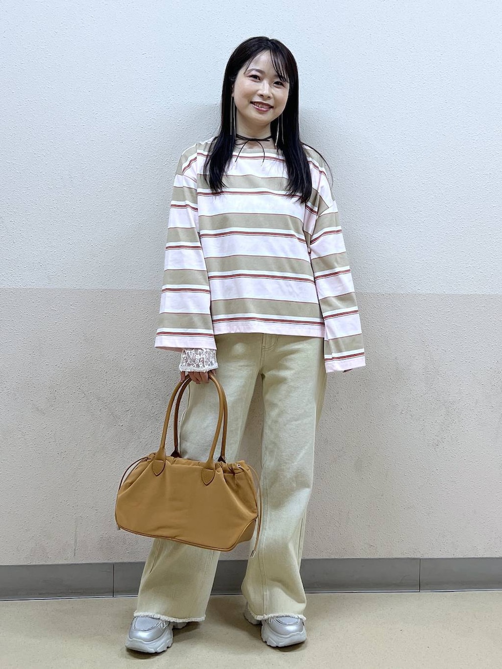 ホワイト系のTシャツ/カットソー、ブラウン系のハンドバッグ、ベージュ系のデニムパンツを着用したレディースの冬コーディネートの5枚目の写真