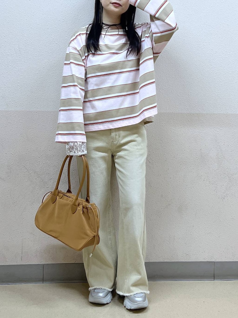 ホワイト系のTシャツ/カットソー、ブラウン系のハンドバッグ、ベージュ系のデニムパンツを着用したレディースの冬コーディネートの7枚目の写真