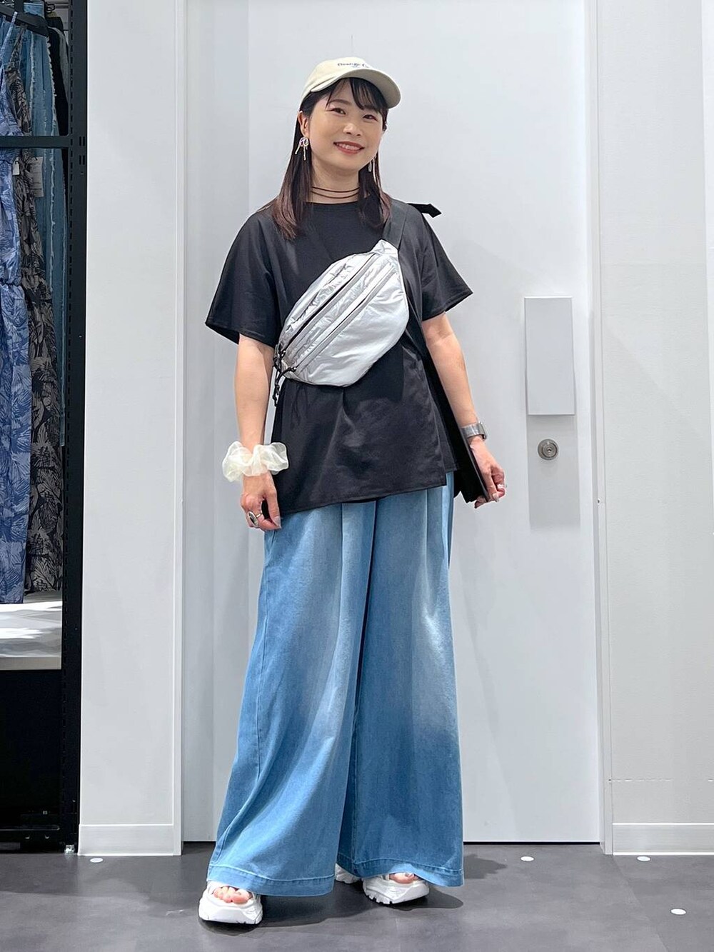 シルバー系のボディバッグ/ウエストポーチ、ホワイト系のスニーカー、ブルー系のデニムパンツを着用したレディースの夏コーディネートの4枚目の写真