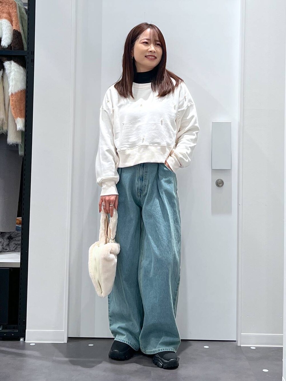 ホワイト系のショルダーバッグ、ブラック系のブーツ、ホワイト系のスウェットを着用したレディースの冬コーディネートの4枚目の写真