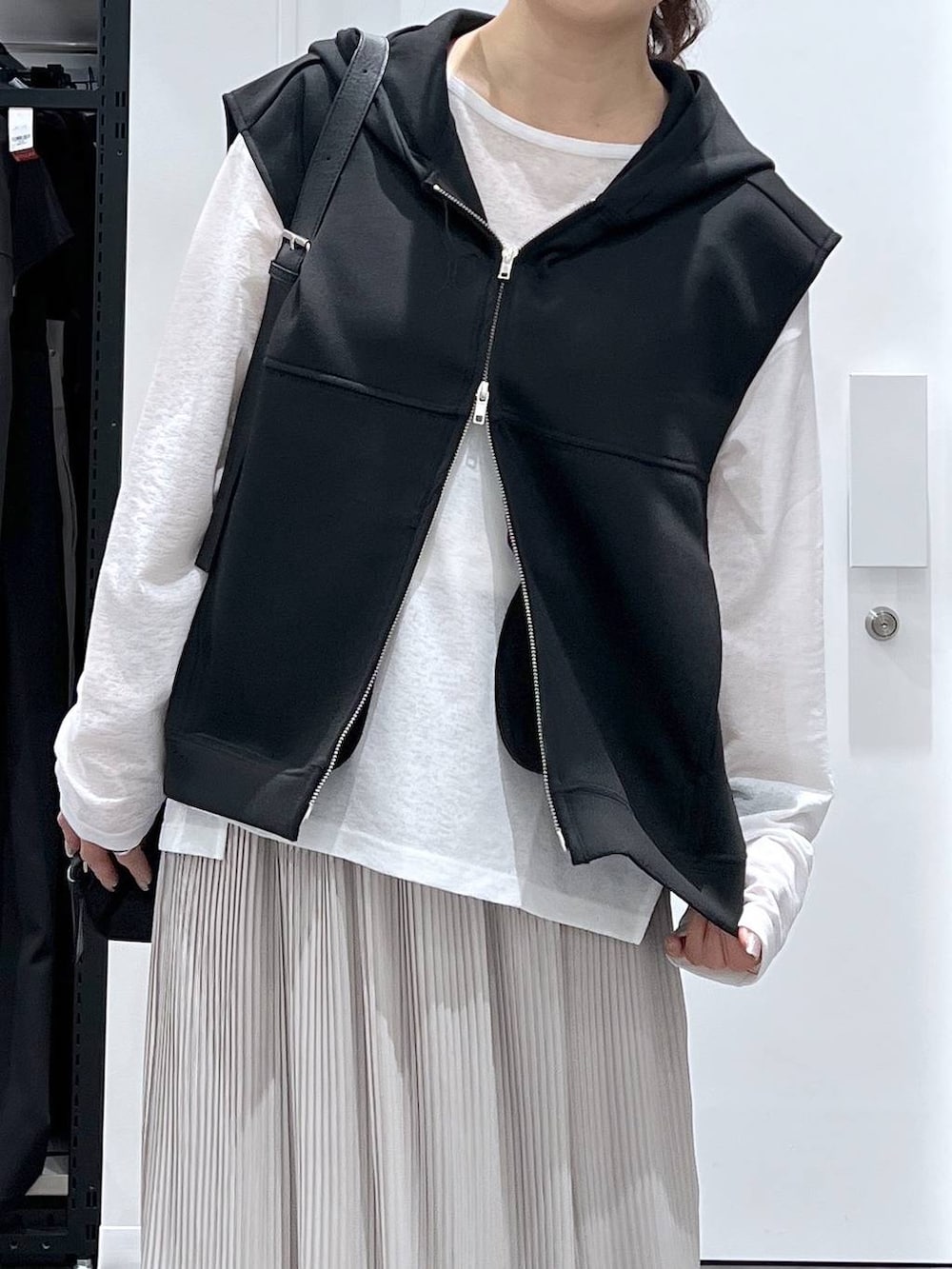 ブラック系のスニーカー、ブラック系のショルダーバッグ、ブラック系のベストを着用したレディースの春コーディネートの4枚目の写真