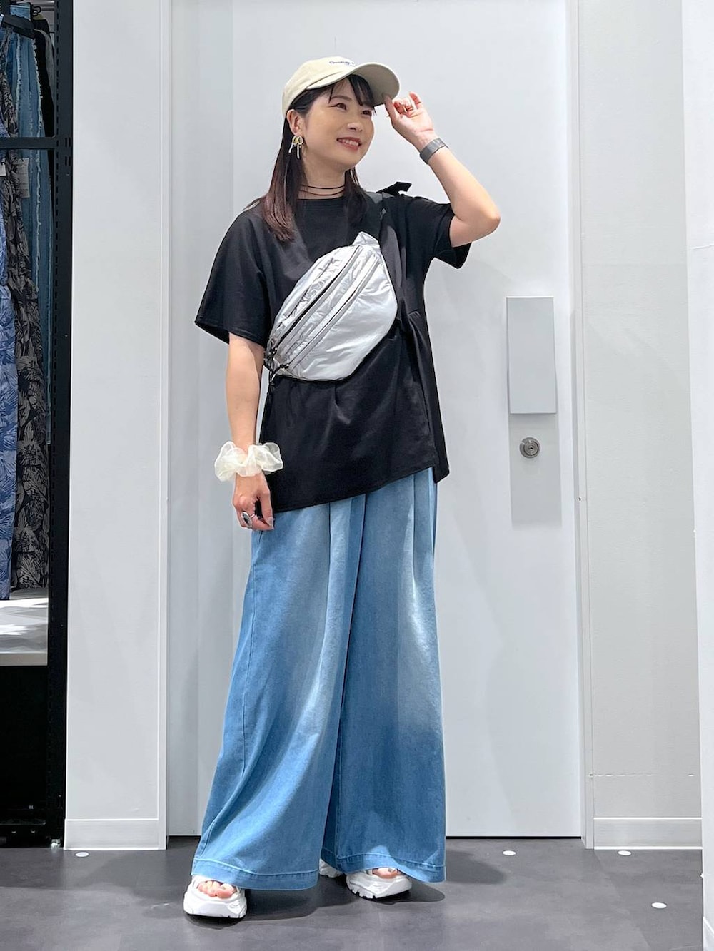 シルバー系のボディバッグ/ウエストポーチ、ホワイト系のスニーカー、ブルー系のデニムパンツを着用したレディースの夏コーディネートの5枚目の写真