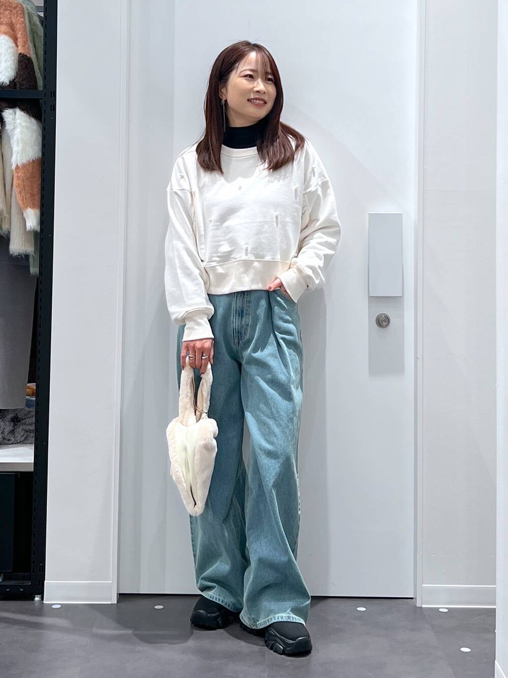 ホワイト系のショルダーバッグ、ブラック系のブーツ、ホワイト系のスウェットを着用したレディースの冬コーディネートの2枚目の写真