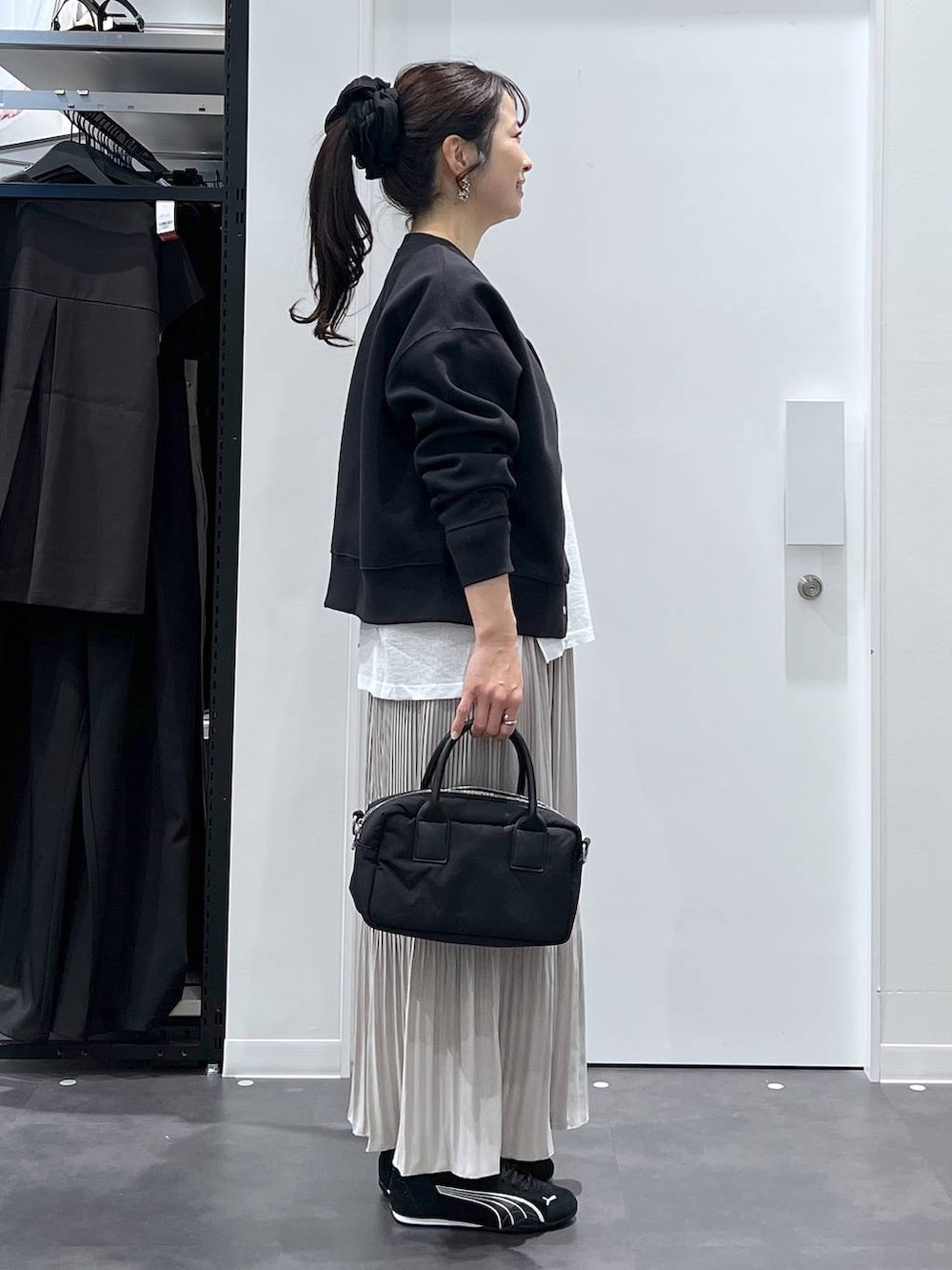 ブラック系のスニーカー、ブラック系のカーディガン/ボレロ、ベージュ系のスカートを着用したレディースの春コーディネートの2枚目の写真