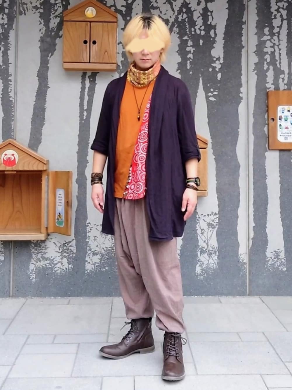 オレンジ系のTシャツ/カットソー、ブラック系のカーディガン/ボレロ、ブラウン系のパンツを着用したメンズの冬コーディネートの2枚目の写真