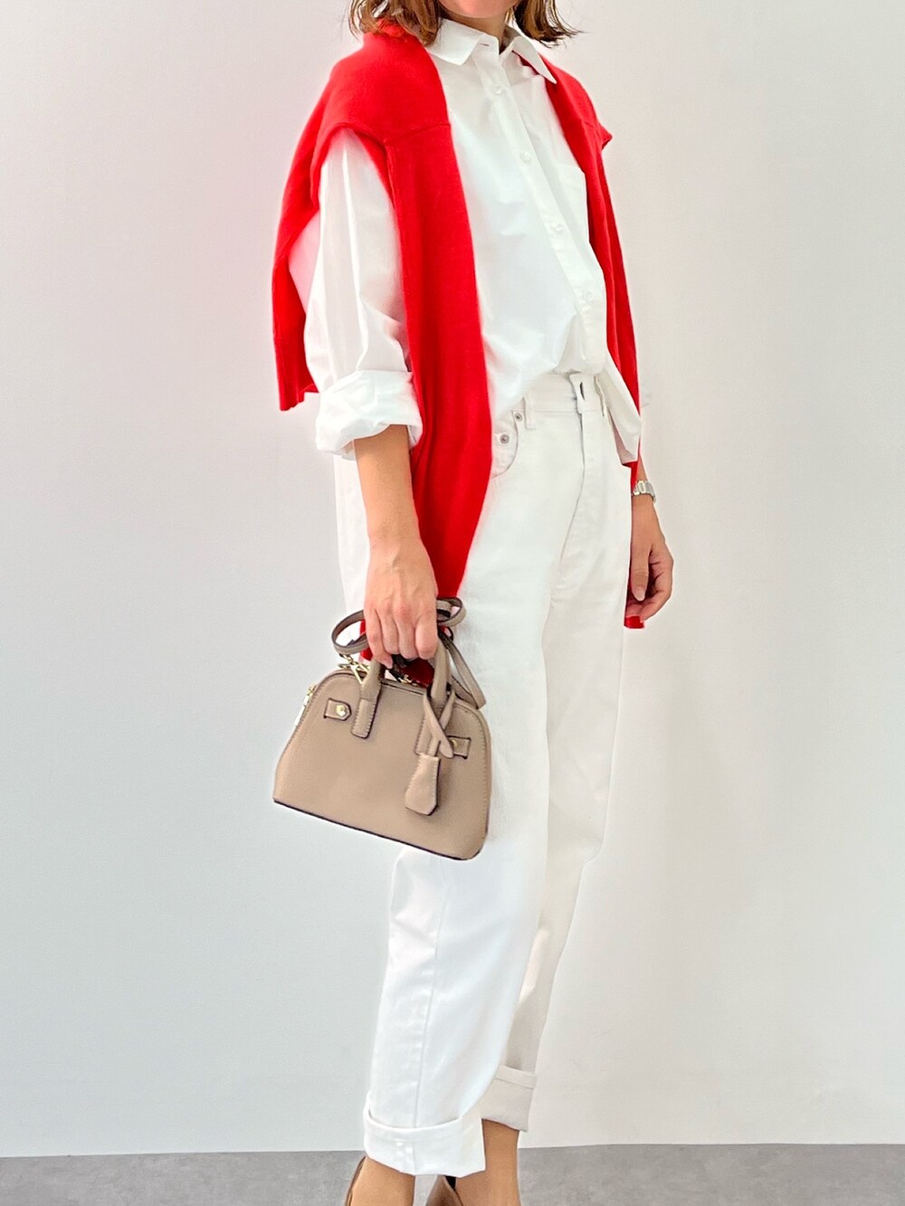 レッド系のニット/セーター、ホワイト系のシャツ/ブラウス、ホワイト系のパンツを着用したレディースの冬コーディネートの2枚目の写真