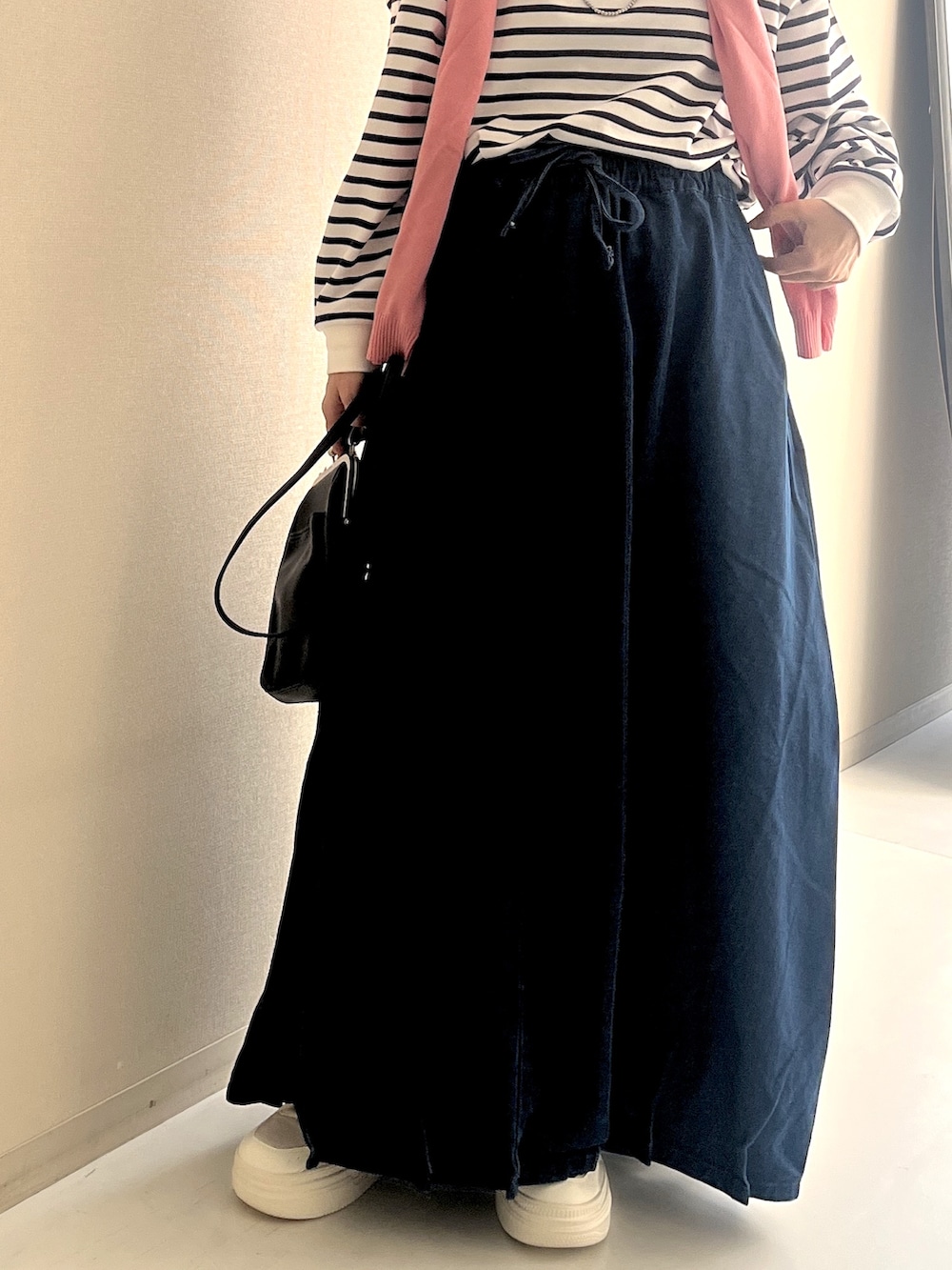 ホワイト系のTシャツ/カットソー、ブルー系のデニムスカート、ピンク系のカーディガン/ボレロを着用したレディースの冬コーディネートの6枚目の写真