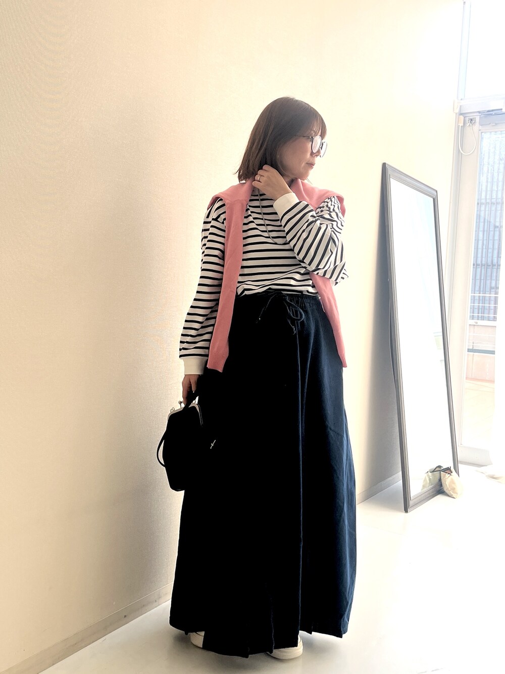 ホワイト系のTシャツ/カットソー、ブルー系のデニムスカート、ピンク系のカーディガン/ボレロを着用したレディースの冬コーディネートの2枚目の写真