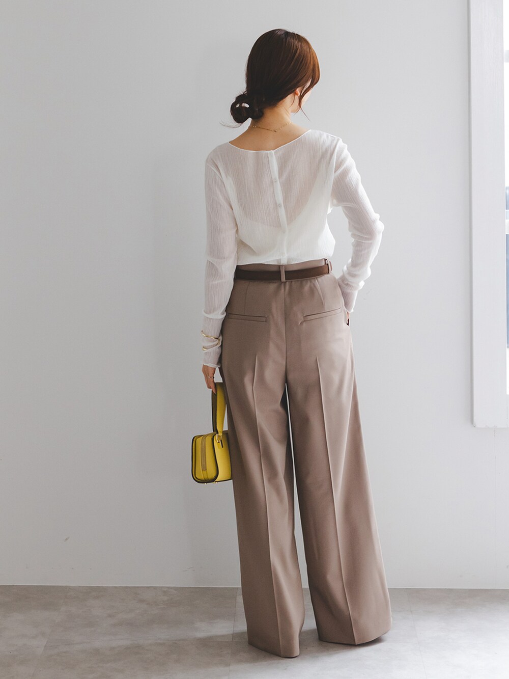 ホワイト系のTシャツ/カットソー、ブラウン系のスラックス、イエロー系のショルダーバッグを着用したレディースの冬コーディネートの3枚目の写真