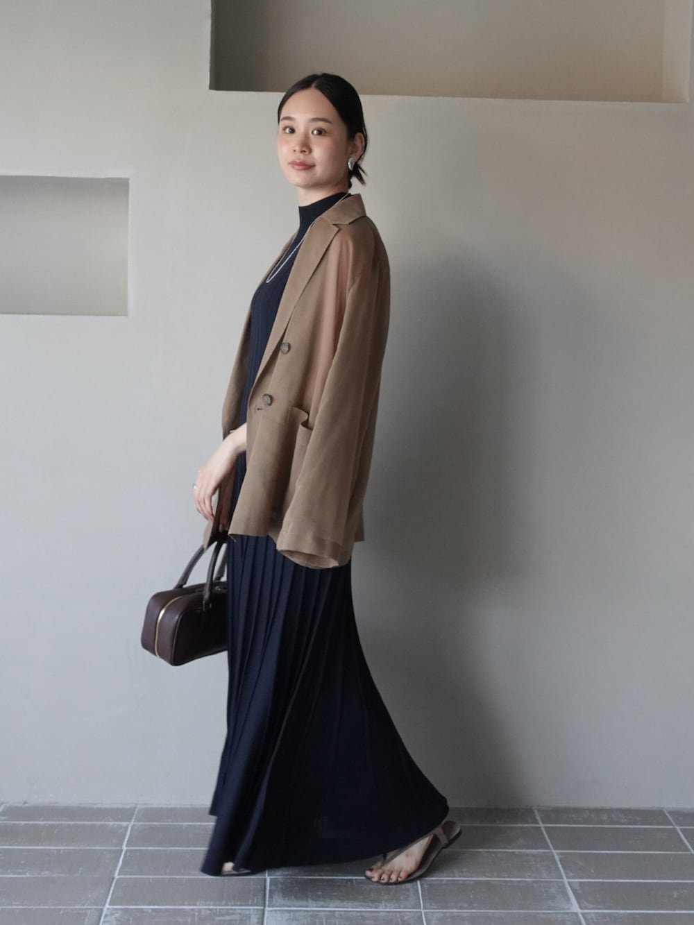 ブラウン系のテーラードジャケット、ブルー系のワンピース、ブラウン系のボストンバッグを着用したレディースの夏コーディネートの2枚目の写真