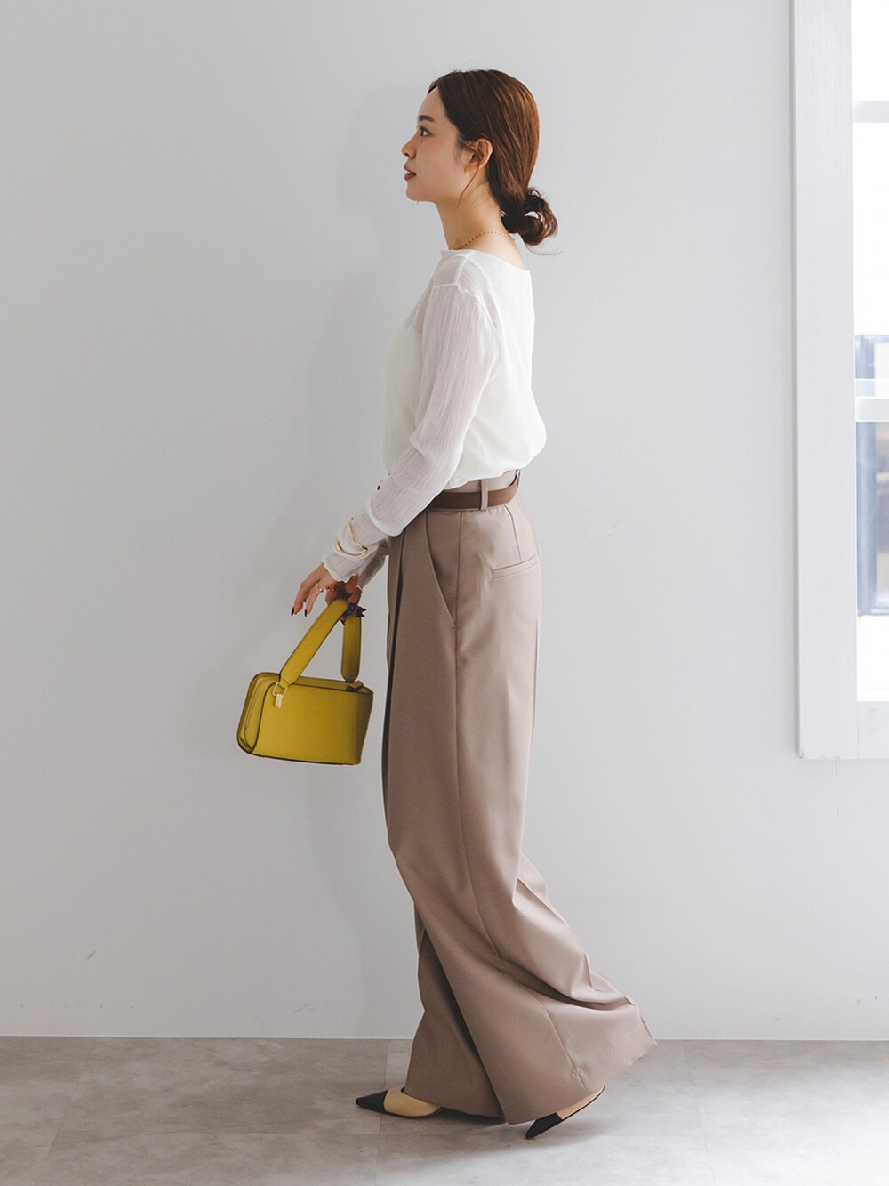 ホワイト系のTシャツ/カットソー、ブラウン系のスラックス、イエロー系のショルダーバッグを着用したレディースの冬コーディネートの2枚目の写真