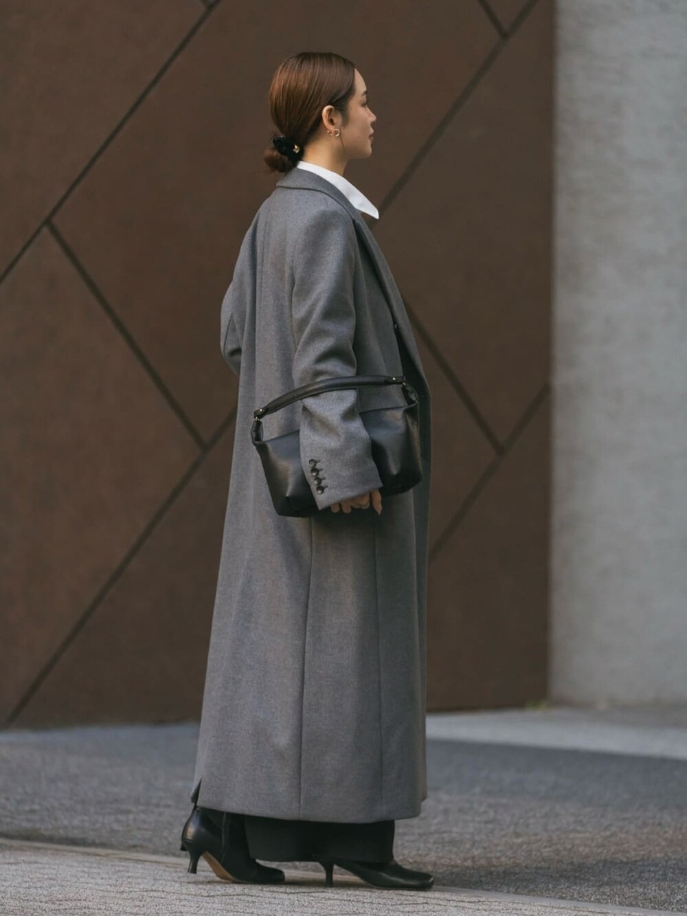 グレー系のチェスターコート、グレー系のTシャツ/カットソー、ブラック系のショルダーバッグを着用したレディースの冬コーディネートの2枚目の写真