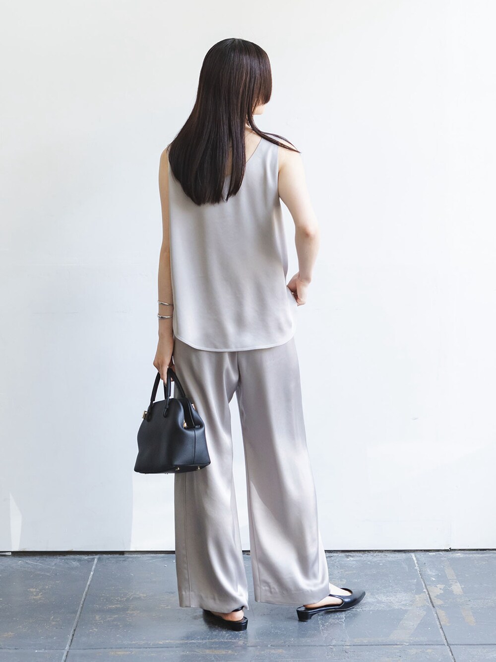 グレー系のタンクトップ、グレー系のスラックス、ブラック系のショルダーバッグを着用したレディースの秋コーディネートの3枚目の写真
