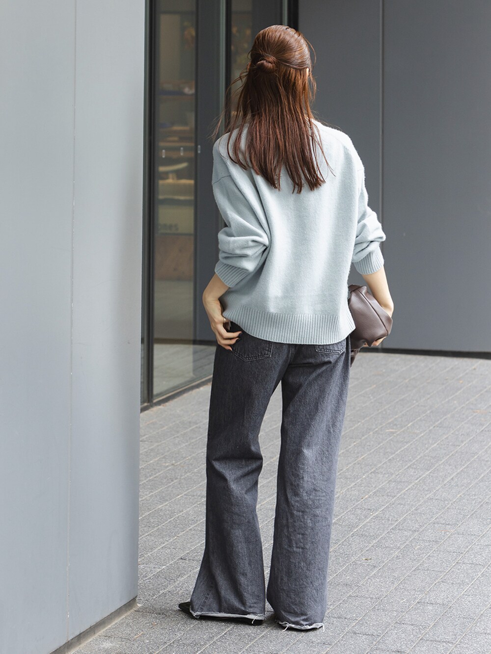 ブルー系のニット/セーター、ブラック系のデニムパンツ、ブラウン系のショルダーバッグを着用したレディースの秋コーディネートの3枚目の写真
