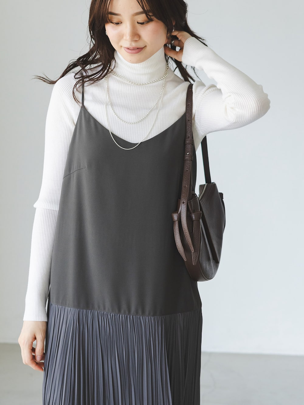 グレー系のワンピース、ホワイト系のニット/セーター、ブラウン系のショルダーバッグを着用したレディースの秋コーディネートの3枚目の写真