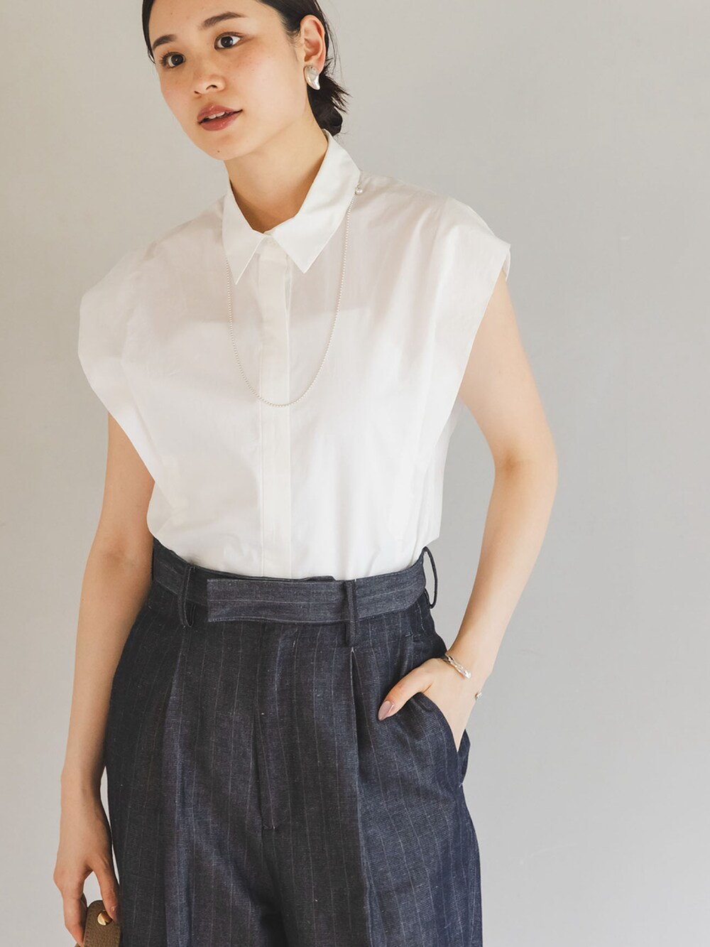 ホワイト系のシャツ/ブラウス、ブルー系のスラックス、ベージュ系のショルダーバッグを着用したレディースの夏コーディネートの4枚目の写真