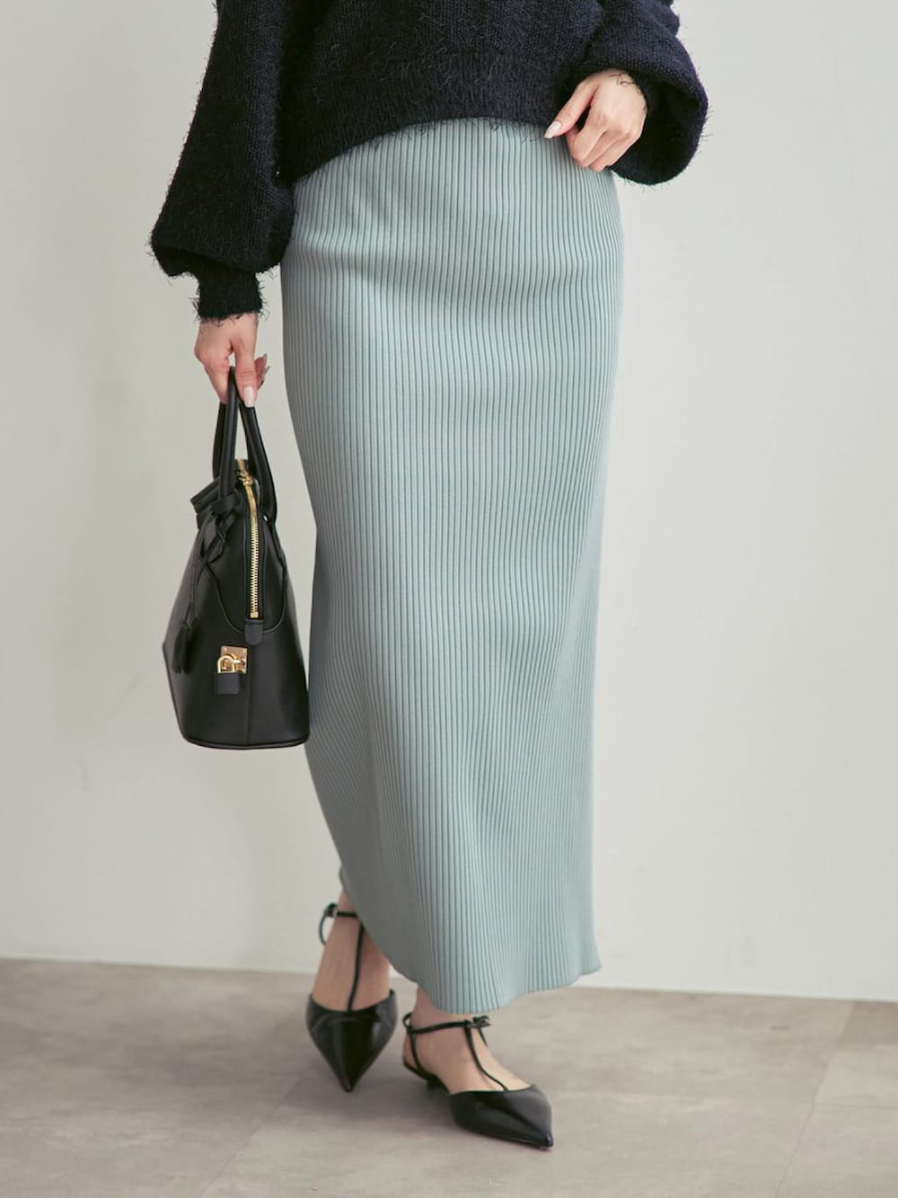 グリーン系のスカート、ブルー系のニット/セーターを着用したレディースの冬コーディネートの3枚目の写真