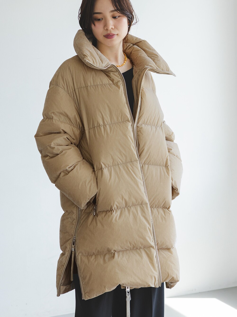 ベージュ系のダウンジャケット/コート、ブラック系のスラックスを着用したレディースの秋コーディネートの3枚目の写真