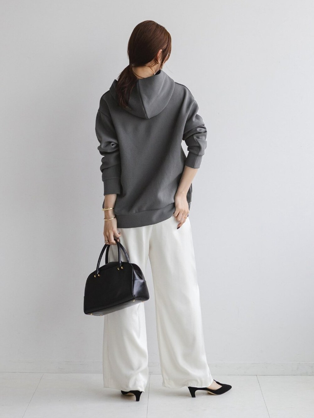 グレー系のスウェット、ホワイト系のスラックス、ブラック系のパンプスを着用したレディースの秋コーディネートの2枚目の写真