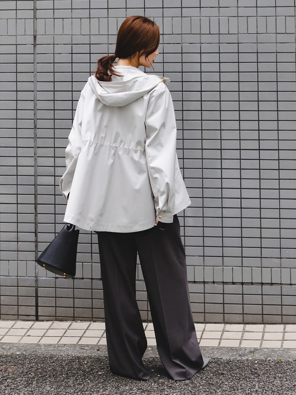 グレー系のマウンテンパーカー、ブルー系のシャツ/ブラウス、グレー系のスラックスを着用したレディースの冬コーディネートの2枚目の写真