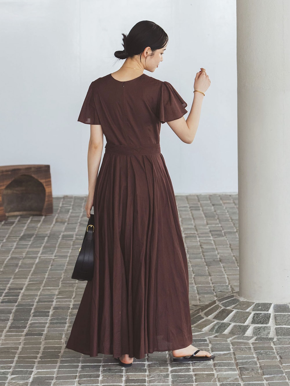 ブラウン系のワンピース、ブラック系のハンドバッグ、ブラック系のサンダルを着用したレディースの夏コーディネートの3枚目の写真