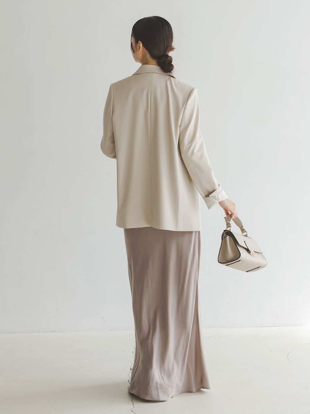 ベージュ系のテーラードジャケット、グレー系のスカート、ベージュ系のショルダーバッグを着用したレディースの秋コーディネートの2枚目の写真