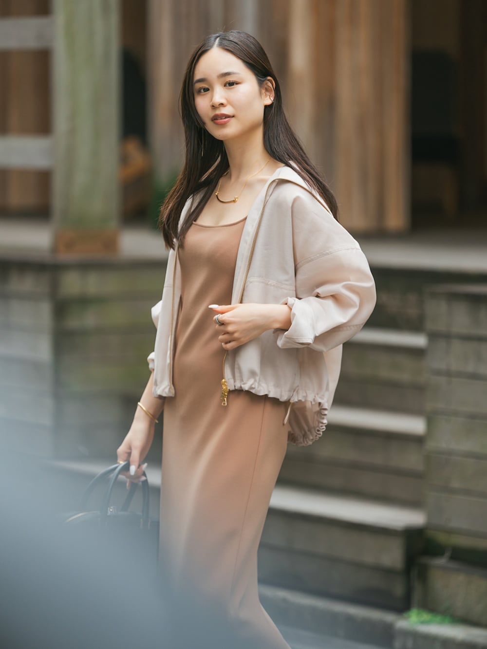 ベージュ系のその他アウター、イエロー系のワンピース、ブラック系のサンダルを着用したレディースの春コーディネートの2枚目の写真