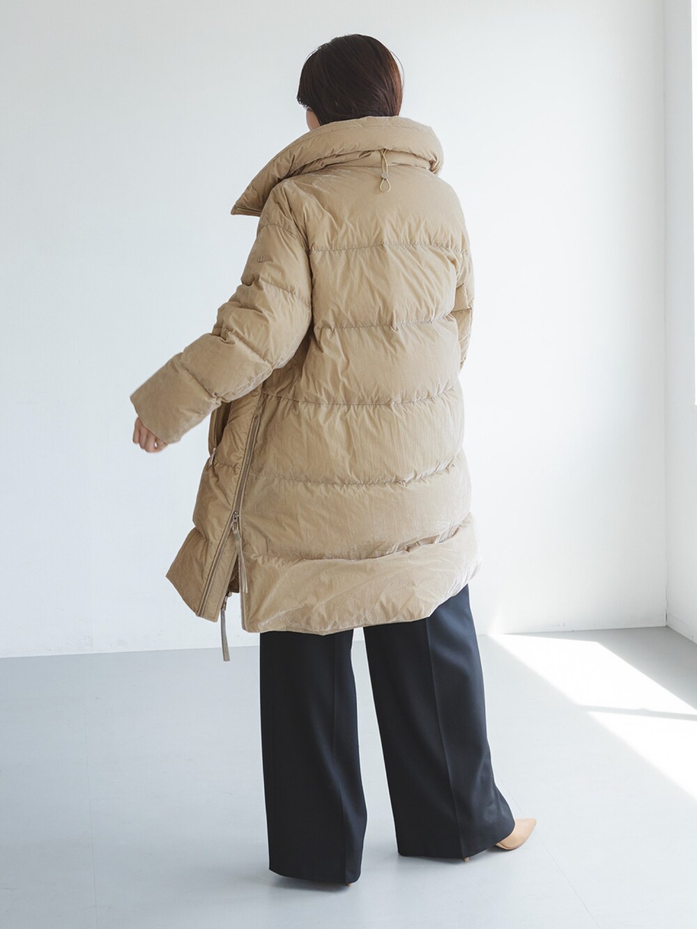 ベージュ系のダウンジャケット/コート、ブラック系のスラックスを着用したレディースの秋コーディネートの2枚目の写真