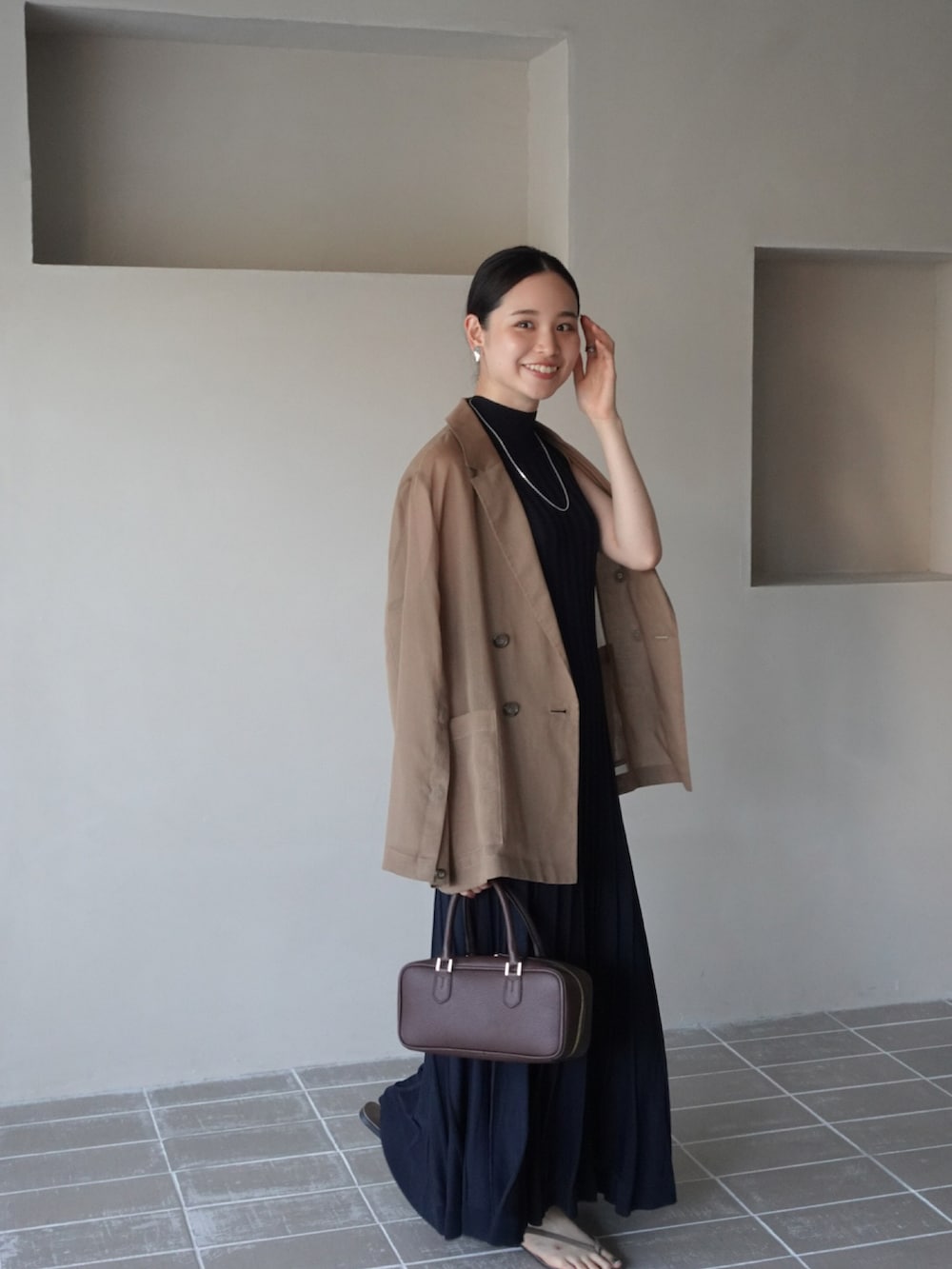 ブラウン系のテーラードジャケット、ブルー系のワンピース、ブラウン系のボストンバッグを着用したレディースの夏コーディネートの3枚目の写真