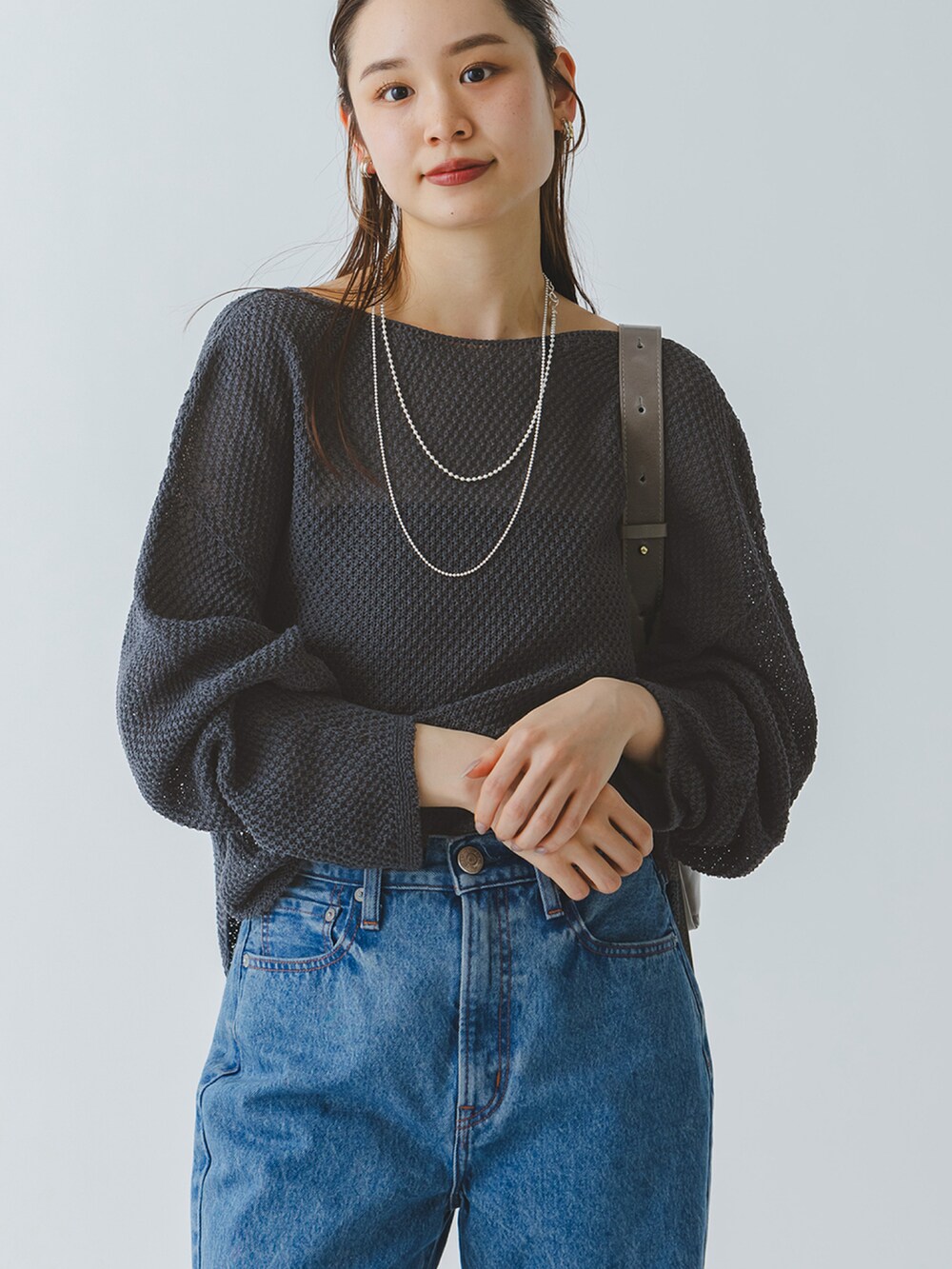 グレー系のニット/セーター、ブルー系のデニムパンツ、ブラック系のサンダルを着用したレディースの春コーディネートの2枚目の写真